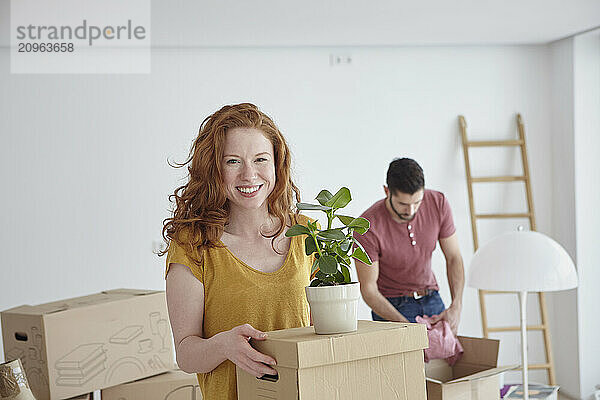 Redhead woman carrying box at new apartment