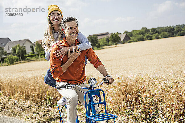 Loving couple enjoying bicycle ride in front of field