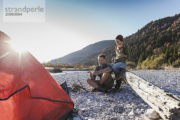 Mature couple spending leisure time camping at riverside