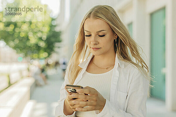 Young woman using smart phone on street