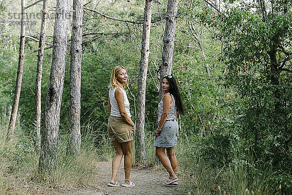 Woman hikers with hands in pockets walking in forest