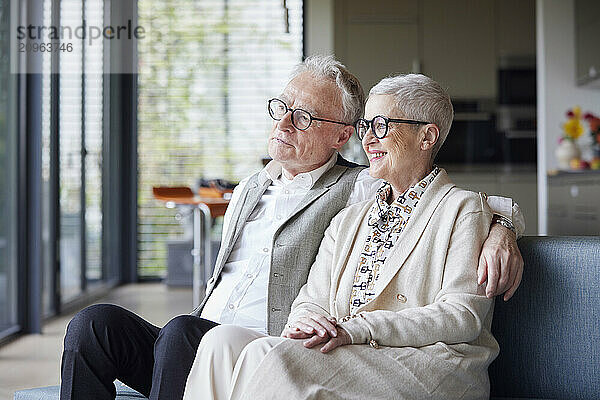 Happy senior couple sitting on couch at home