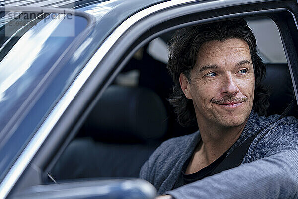 Smiling mature man sitting in car