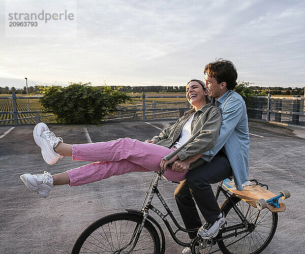 Happy couple riding bicycle at parking lot