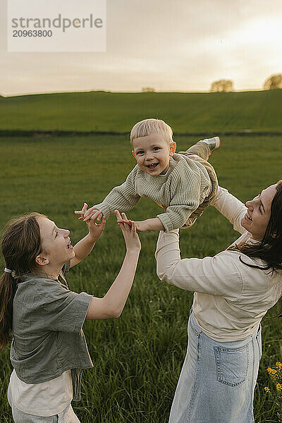 Mother and daughter playing with baby at meadow