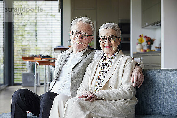 Portrait of happy senior couple sitting on couch at home