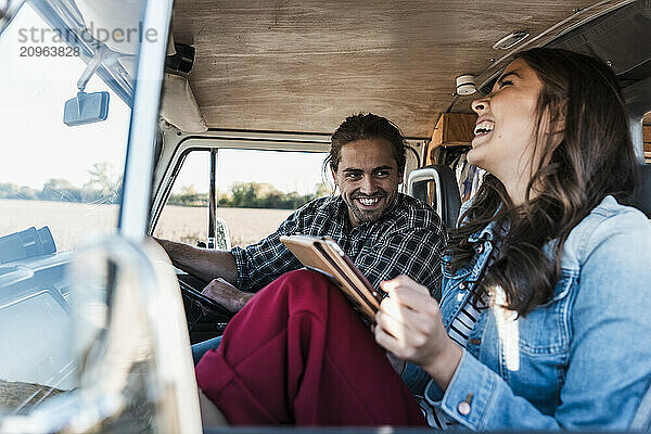 Cheerful young couple laughing in camper van