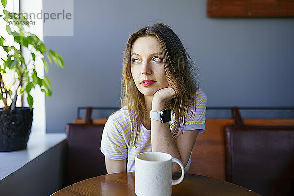 Beautiful woman sitting with coffee cup at table in cafe