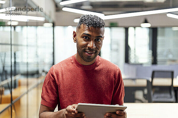 Smiling businessman with tablet PC at office