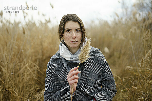 Woman wearing scarf and holding pampas in reeds