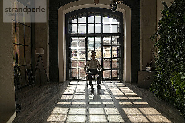 Mature businessman sitting on chair in front of window