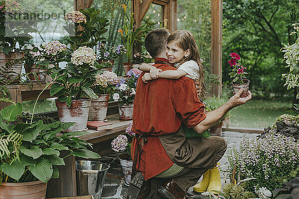 Happy girl embracing father in greenhouse