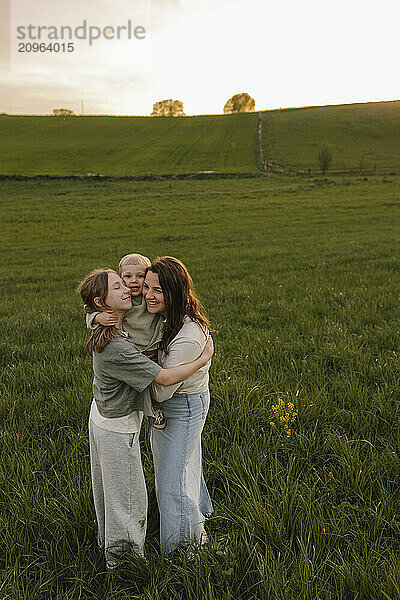 Mother and daughter embracing baby at meadow