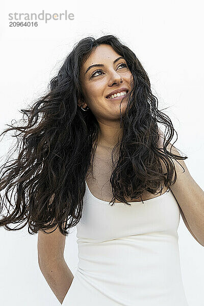 Beautiful woman with hand in hair smiling and standing against white background