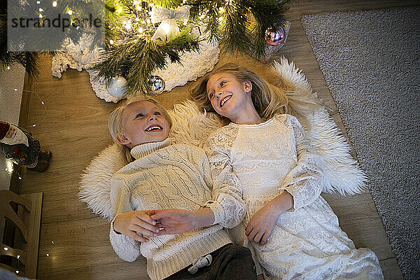 Happy children lying down and enjoying leisure time during Christmas at home