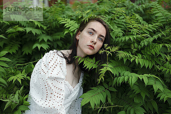 Teenage girl surrounded by leaves in garden