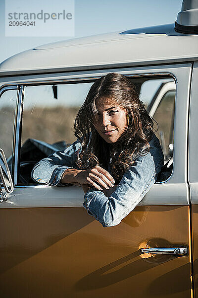 Young woman leaning out of window in van