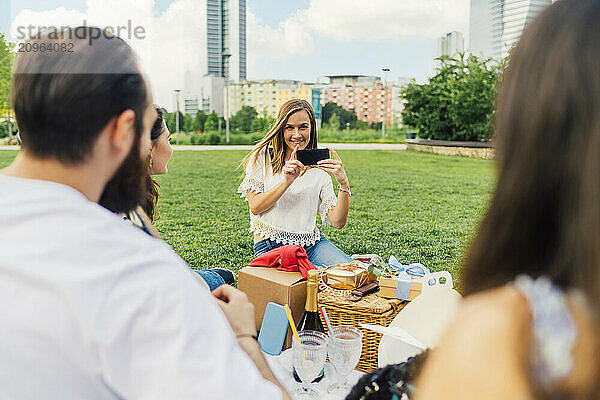 Happy woman photographing friends with smart phone