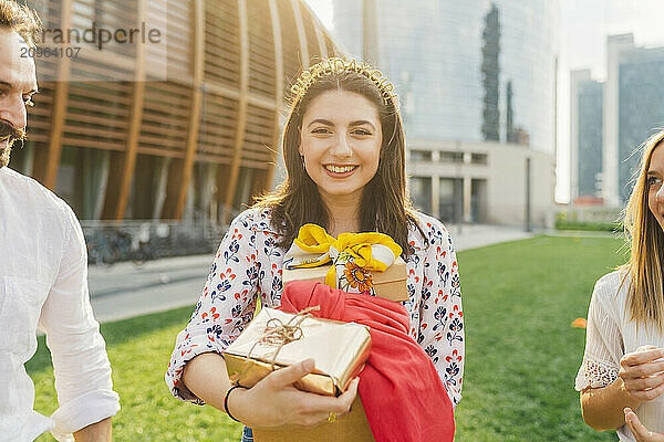 Happy woman holding gifts with friends