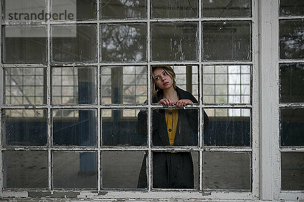 Young woman looking through window frame at home