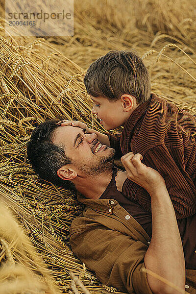 Father and son lying on a wheat field in the summer.