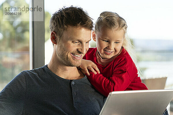 Happy father and daughter watching tablet PC at home