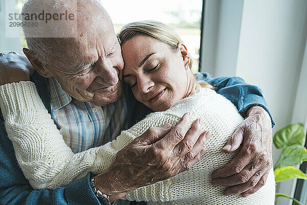 Smiling blond woman hugging father at home