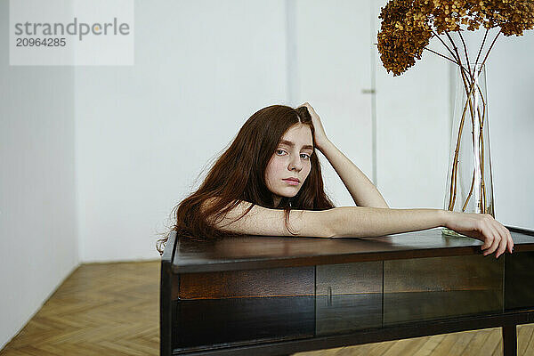 Woman with hand in hair leaning on table at home