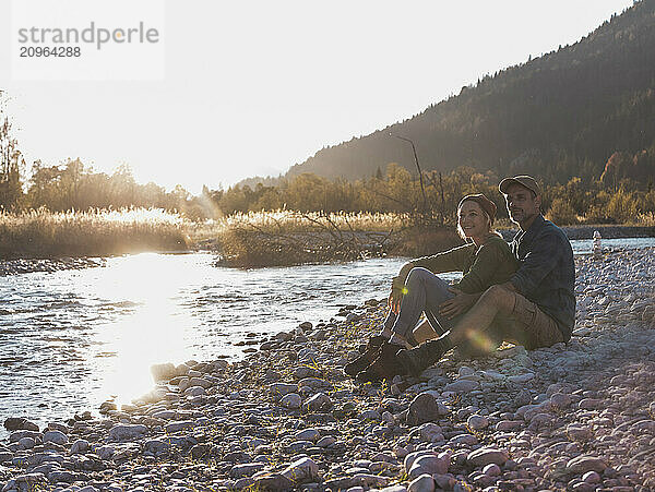 Mature man sitting with girlfriend near riverside