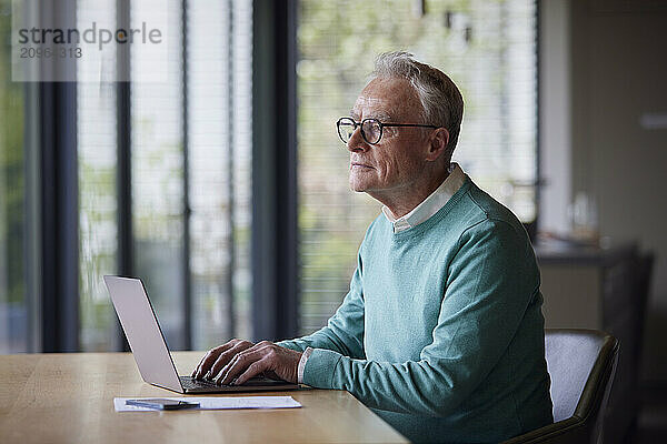 Senior man using laptop at table at home