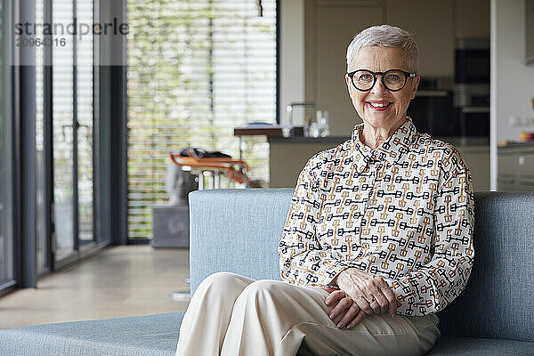 Portrait of smiling senior woman sitting on couch at home