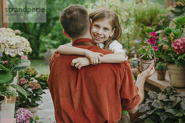 Smiling girl embracing father in plant nursery