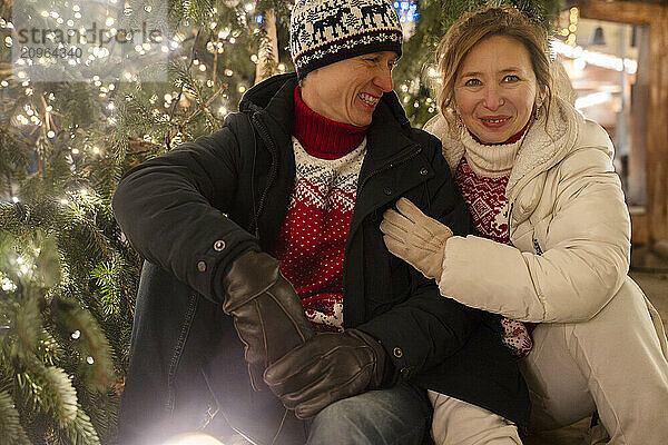 Smiling couple sitting under christmas tree