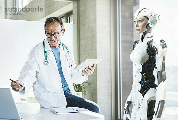 Focused doctor using laptop to operate cyborg in office