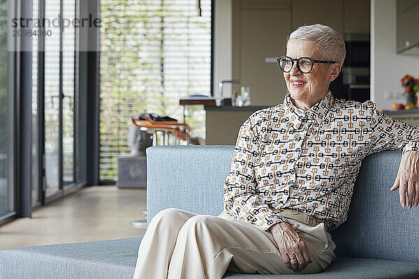 Smiling senior woman sitting on couch at home