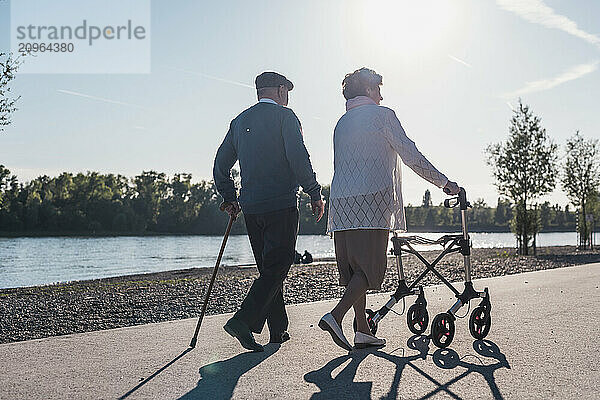 Senior couple together walking near river on sunny day