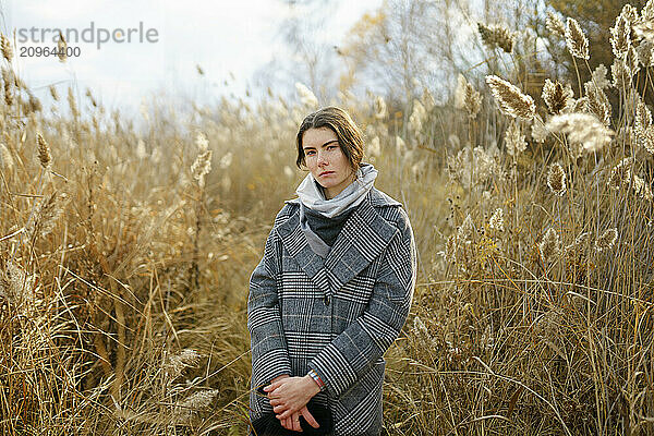 Woman with hands clasped standing amidst reeds