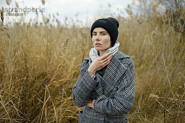 Young woman holding scarf and standing in reeds