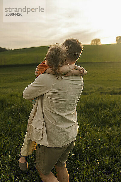 Girl hugging father in meadow