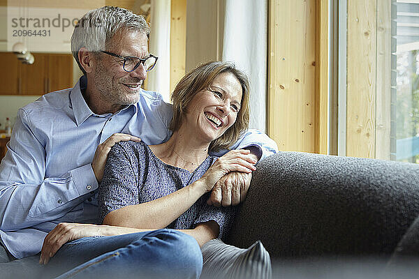 Happy woman sitting with man on sofa at home