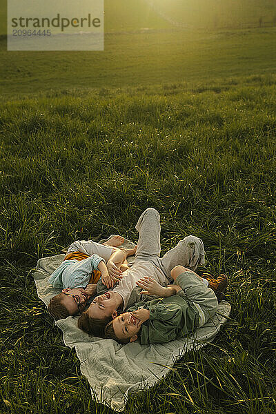 Carefree siblings lying on picnic blanket at meadow