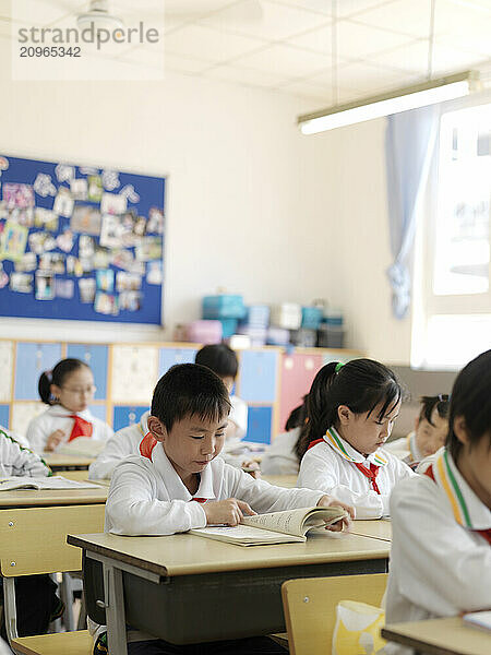 A classroom of young students reading a lesson from their textbook.