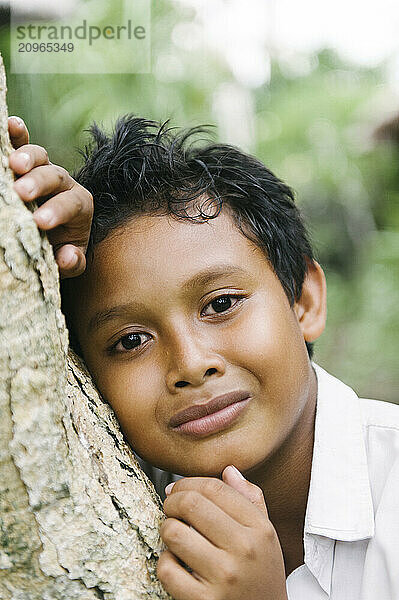 A group of young boys smiling and playing on an open field and climbing a tree