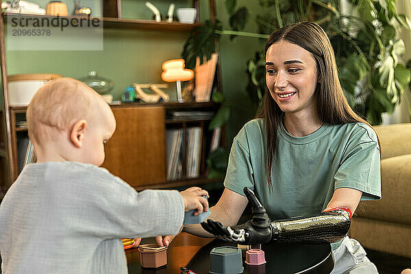 Young woman with prosthesis enjoys playing with baby