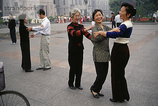 Three women practice dancing the waltz together on the Bund in Shanghai.