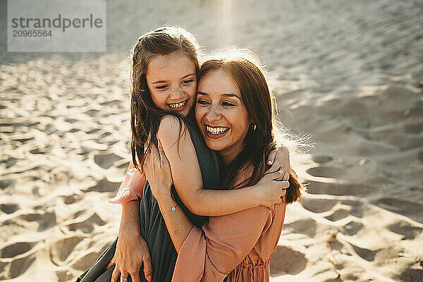 Spanish Happy mother and daughter laughing hugging smiling at beach