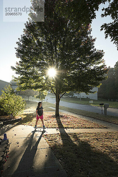 Young girl riding skateboard on sunny fall day