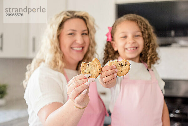 Close up of Mother and daughter holding a cookies smiling