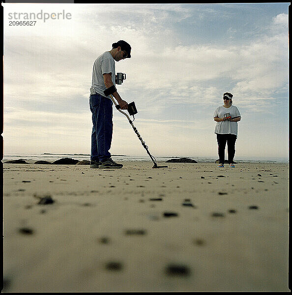 A man uses a metal detector on a beach in Maine. (High speed film)