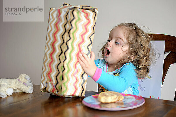 Beautiful excited toddler opening birthday gift